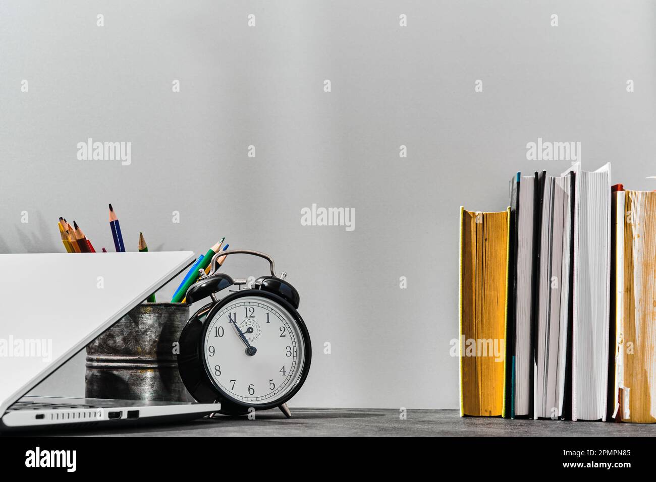 https://c8.alamy.com/comp/2PMPN85/concept-back-to-school-or-teachers-day-idea-pens-pencils-books-an-alarm-clock-and-a-laptop-on-the-table-against-the-background-of-a-gray-board-2PMPN85.jpg