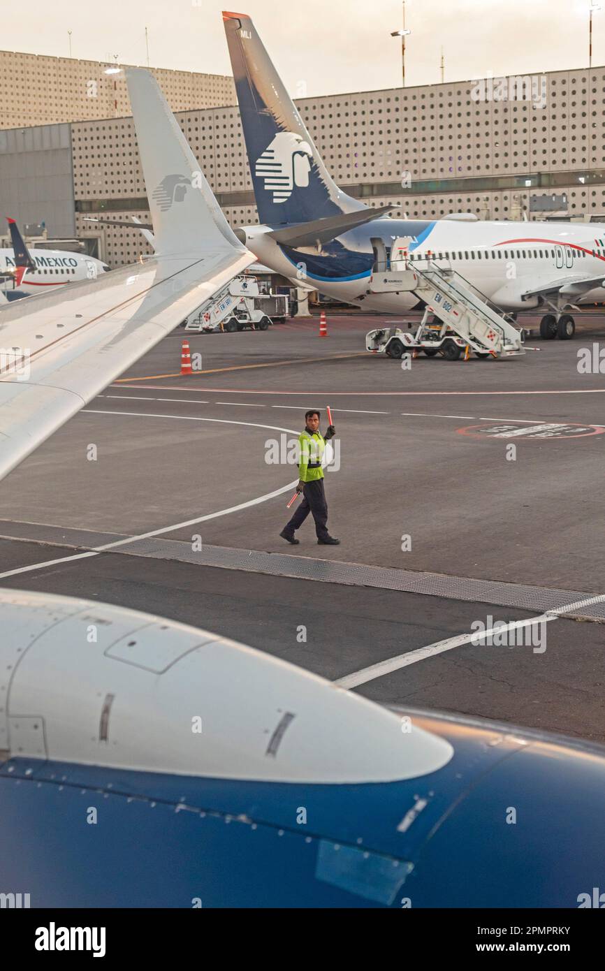 Mexico City, Mexico - A ground crew member helps guide a departing AeroMexico jet away from the gate at  Mexico City International Airport (Aeropuerto Stock Photo