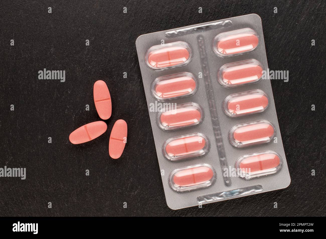 Several medical pills in blister pack on slate stone, macro, top view. Stock Photo