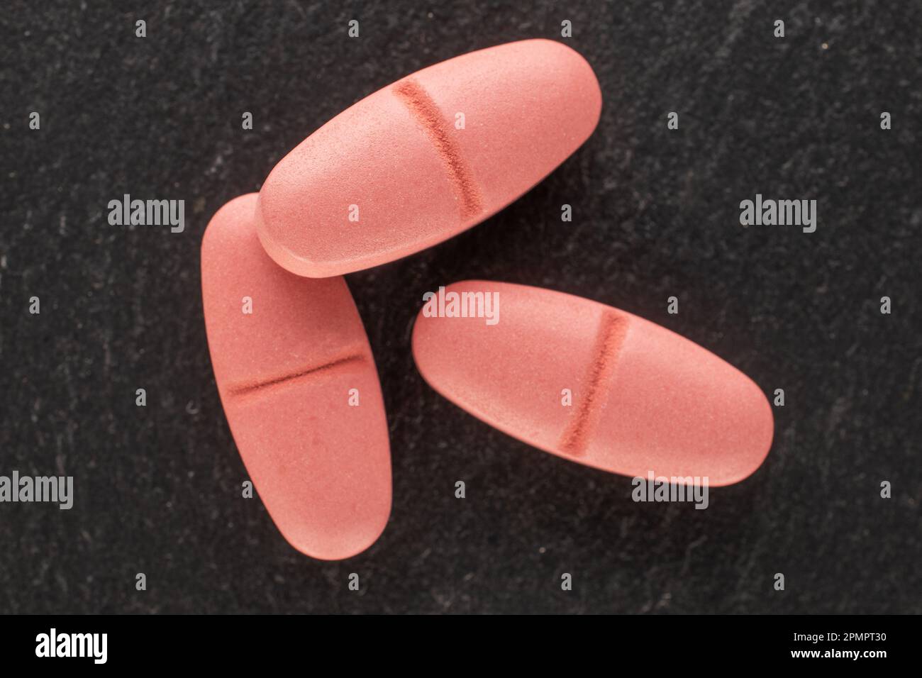 Three medical pills on slate stone, macro, top view. Stock Photo