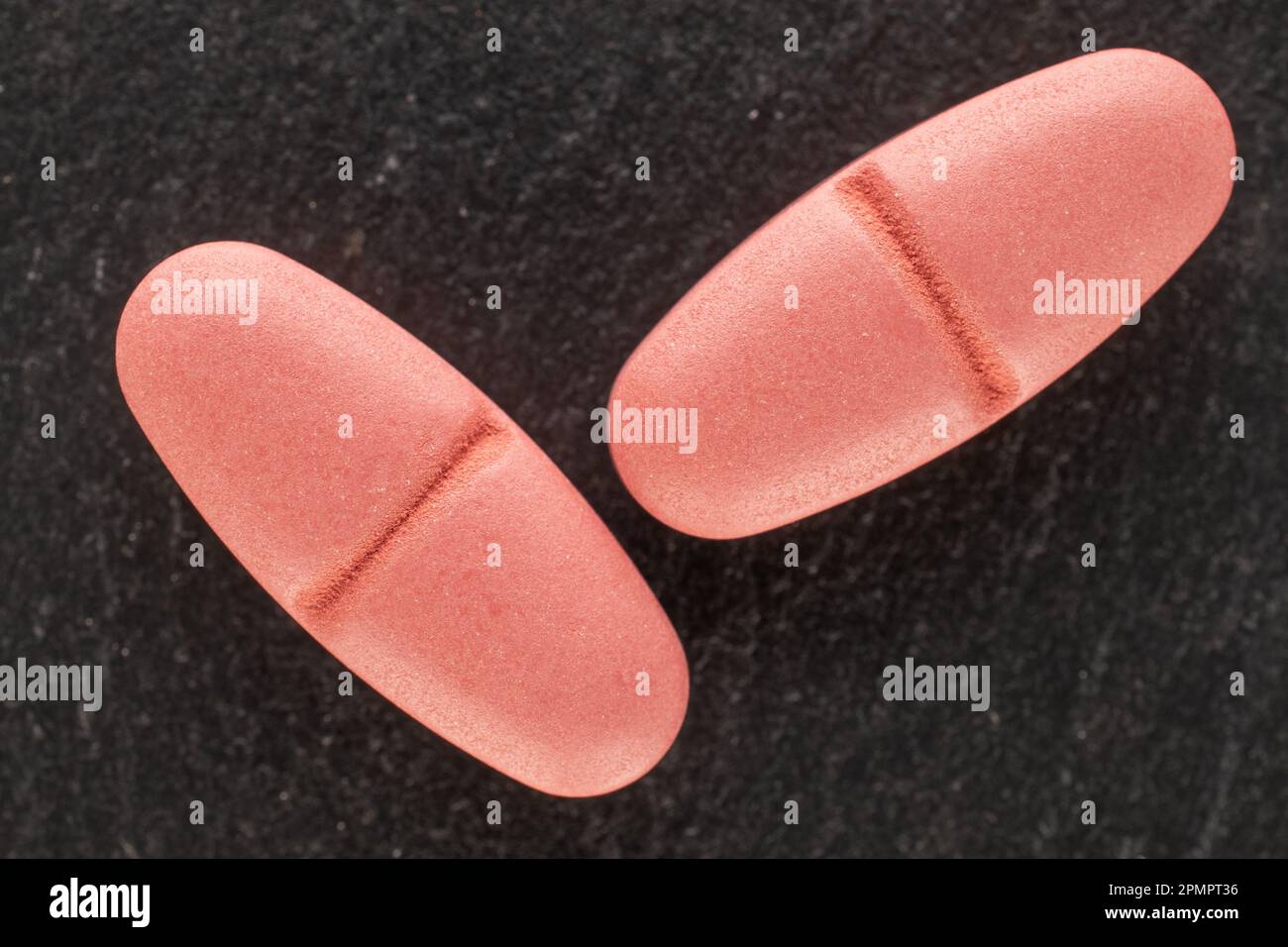 Two medical pills on slate stone, macro, top view. Stock Photo
