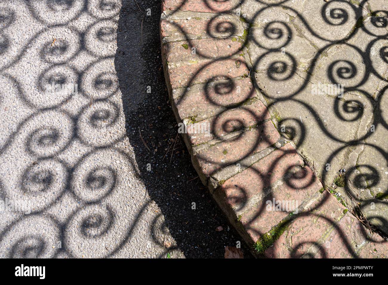 Shadow pattern of wrought iron gate on the pavement or sidewalk Stock Photo