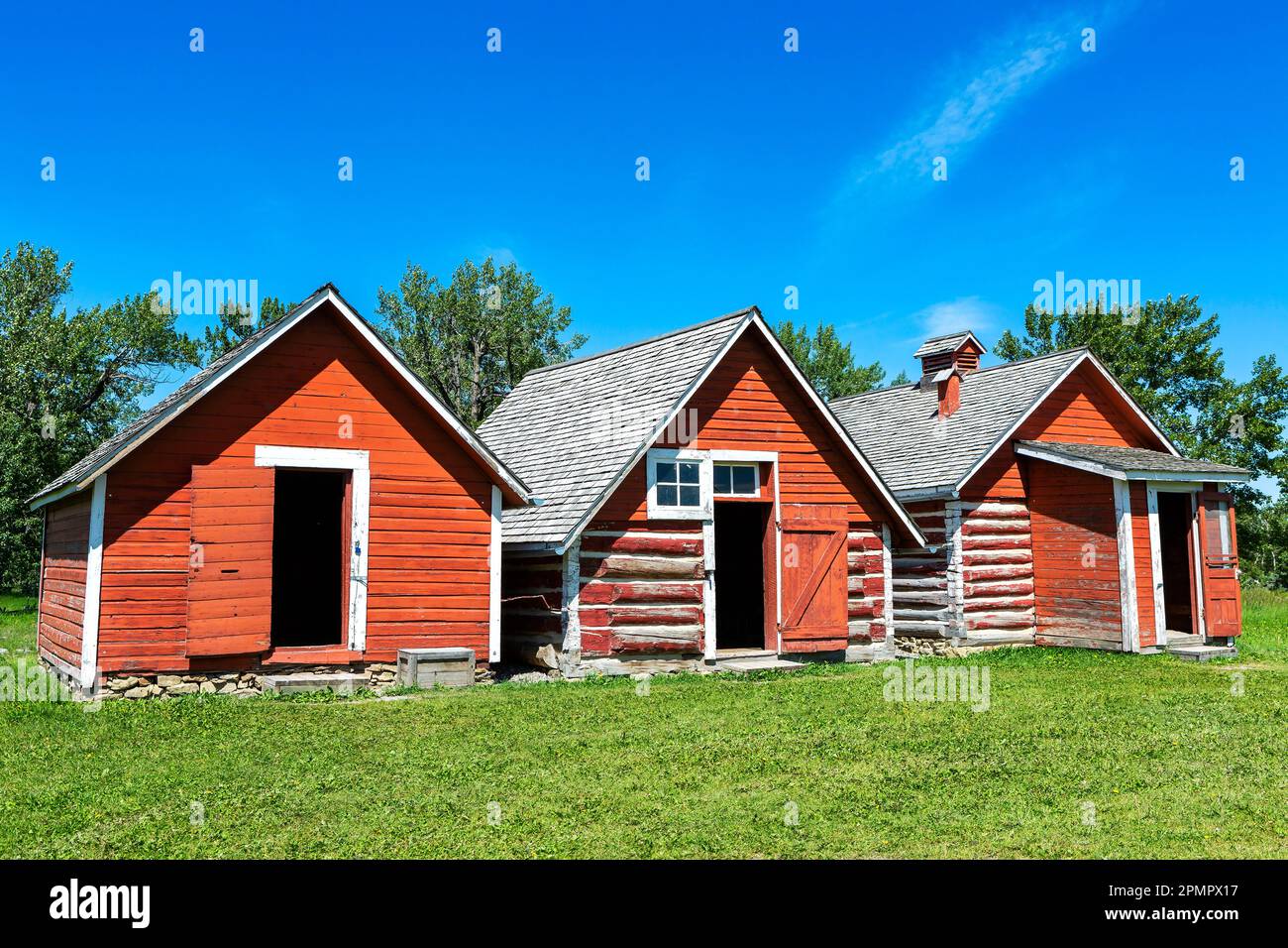 Three old historical red painted buildings with blue sky, South of Longview, Alberta; Alberta, Canada Stock Photo