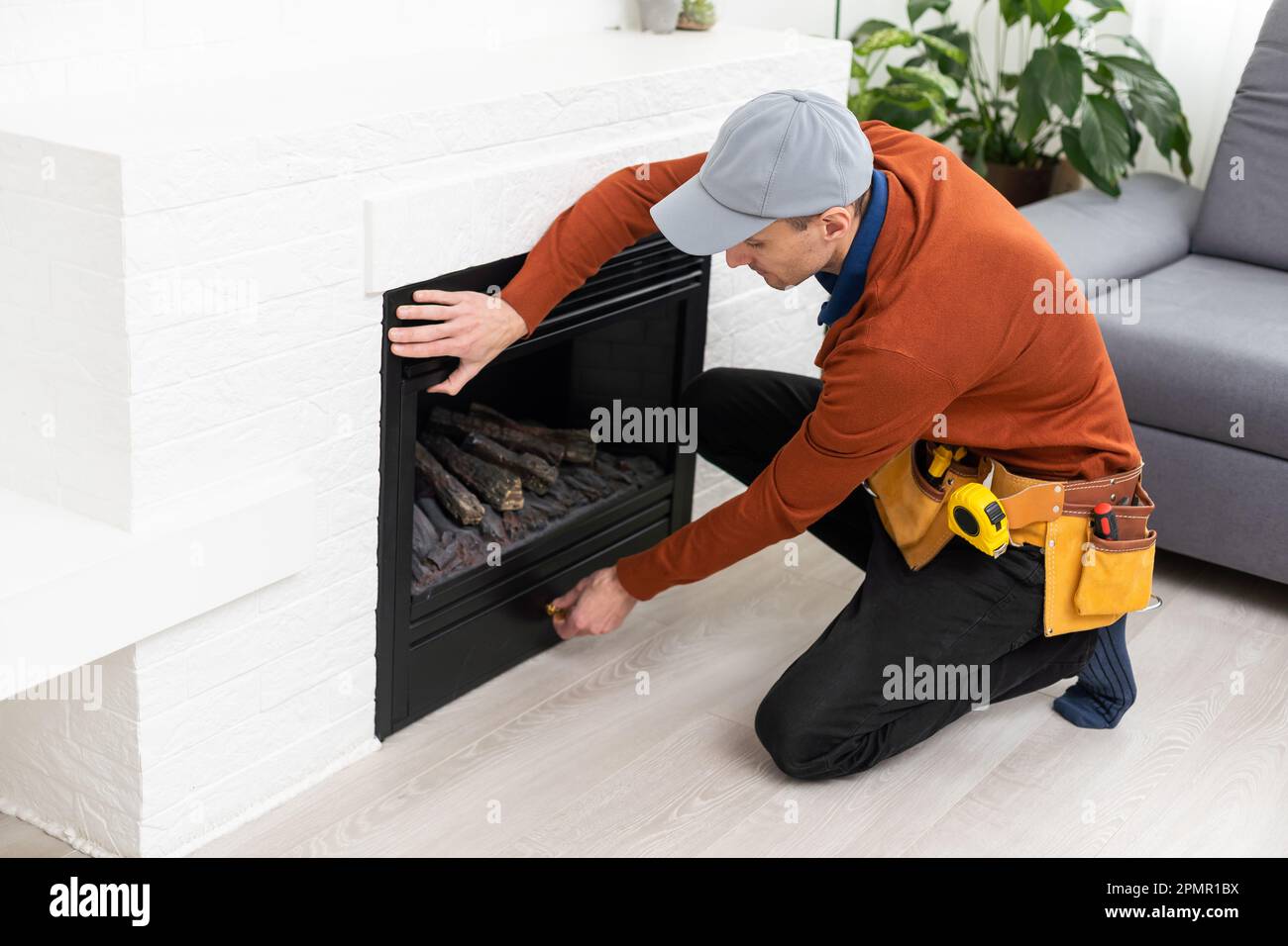 Professional technician sealing electric fireplace with caulk near