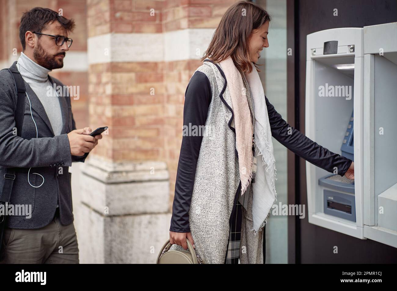 A young elegant man is impatient while waiting in a row for cash machine in a tense atmosphere. Walk, ATM, city Stock Photo