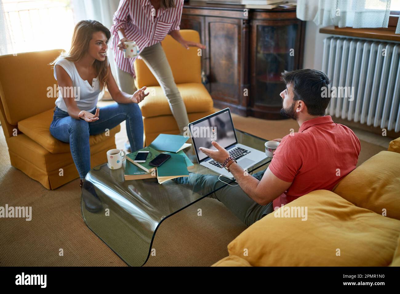 Group of three young students writing paper together at home Stock Photo