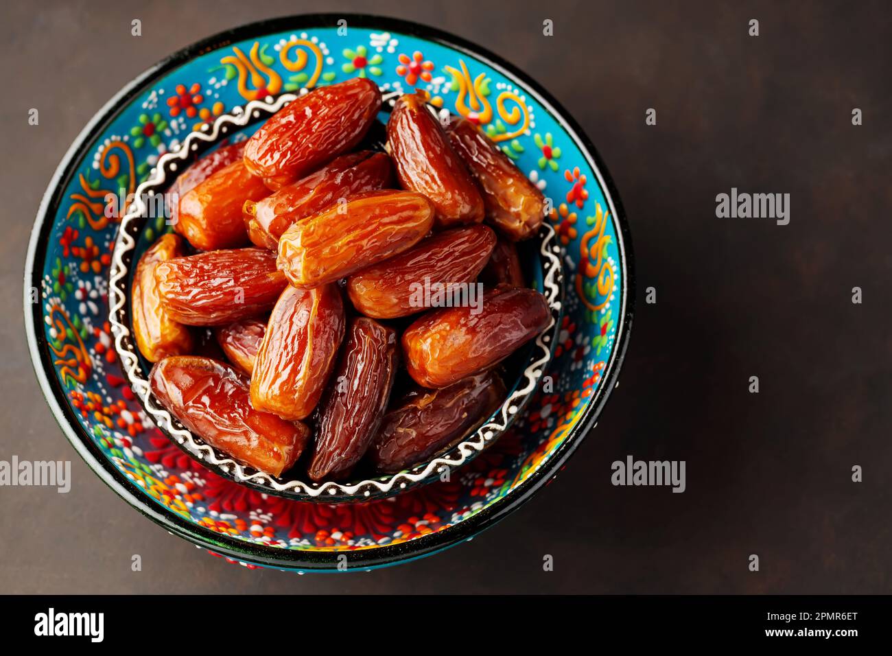 Dried dates in bowl on a dark background. Bowl of pitted dates. Food