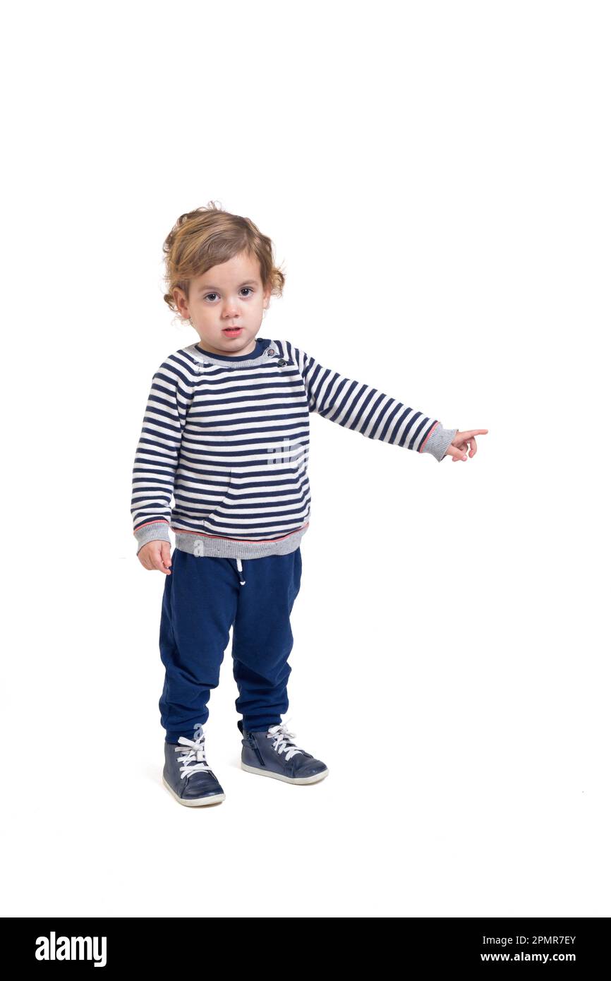 standing baby boy looking at camera and pointing finger to the side on
