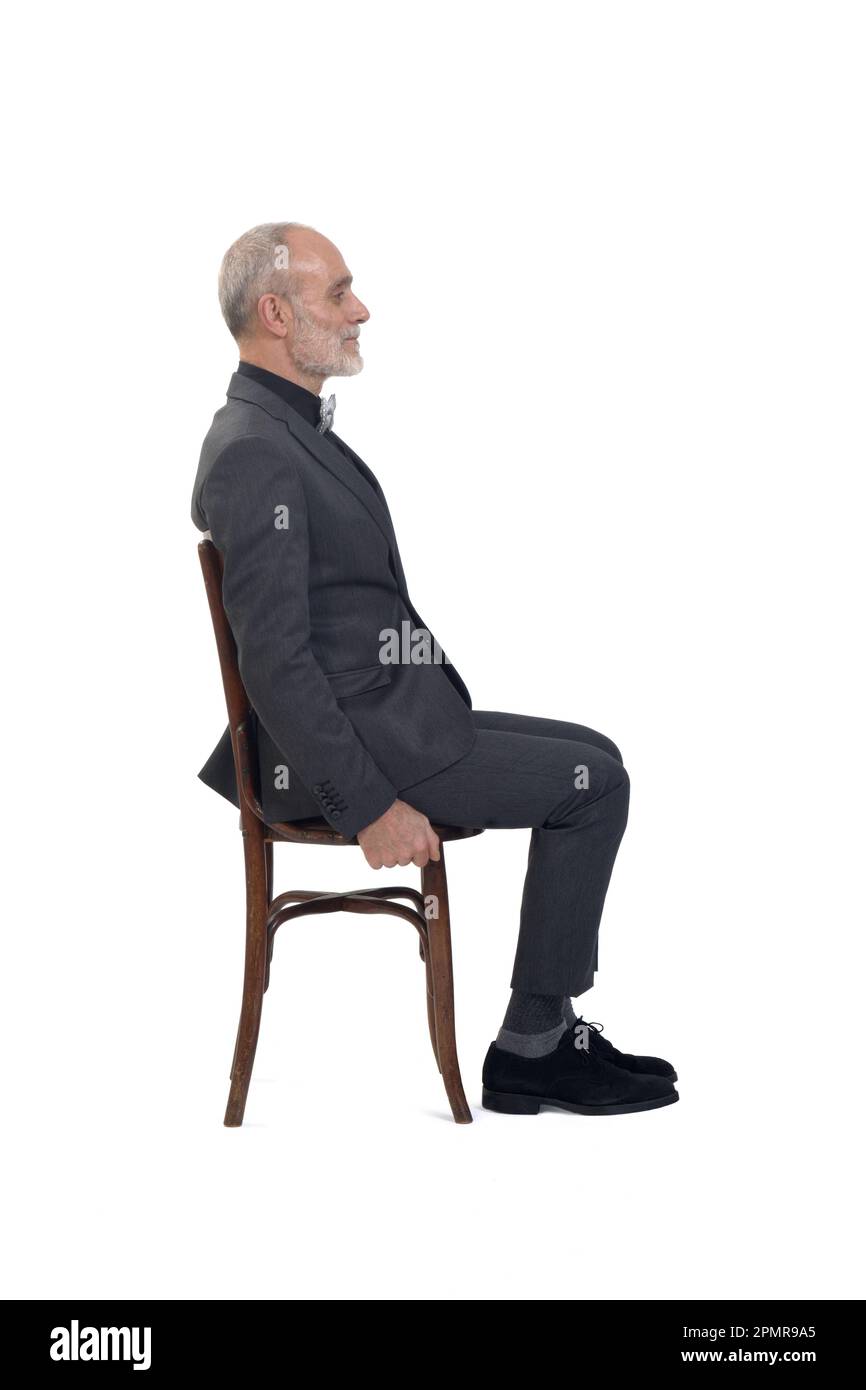 side view of a man sitting  on chair with suit and tie bow on white background Stock Photo