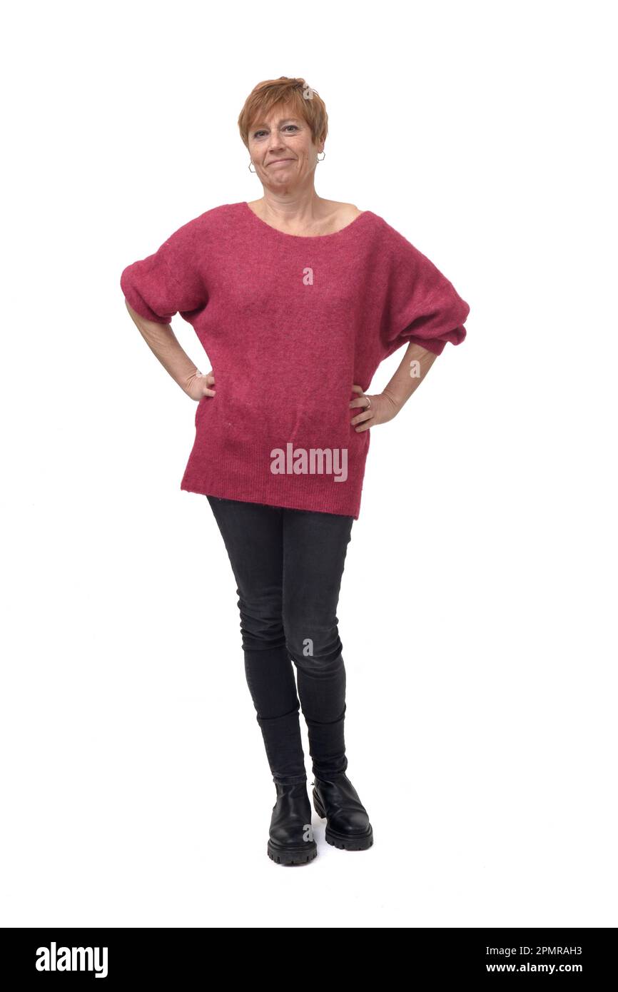 full length portrait of standing woman in tight jean pants and sweater looking at camera with hands akimbo on white background Stock Photo