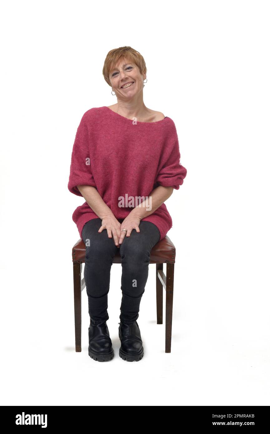 front view of a woman in tight jean pants sitting on chair looking at camera on white background Stock Photo