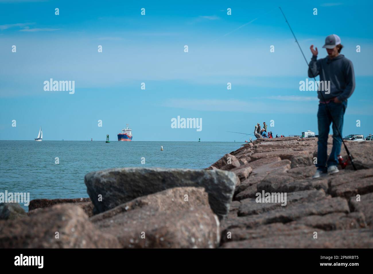 PORT ARANSAS, TX - 12 FEB 2023: The South Jetty at the Gulf of Mexico in Port Aransas, Texas, with marine traffic and people fishing. Stock Photo