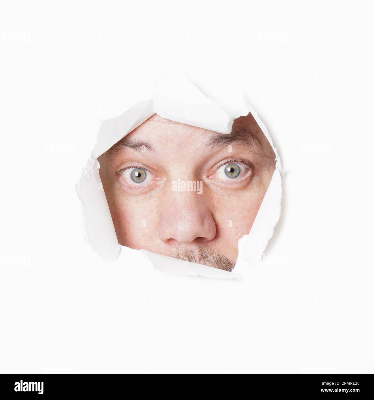 male eyes staring through torn hole voyeurism or stalking concept Stock Photo