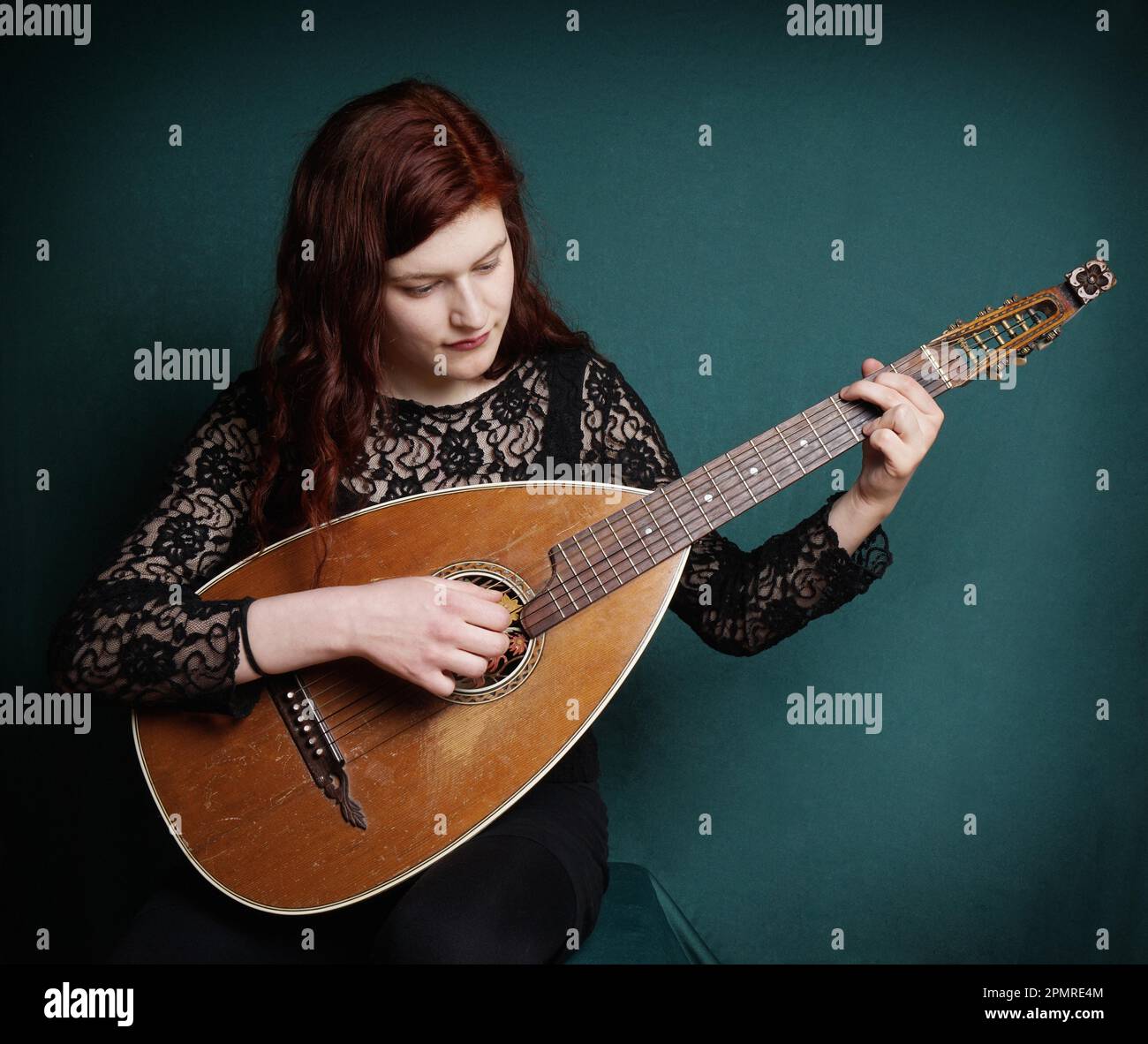young woman playing vintage lute instrument with added filter