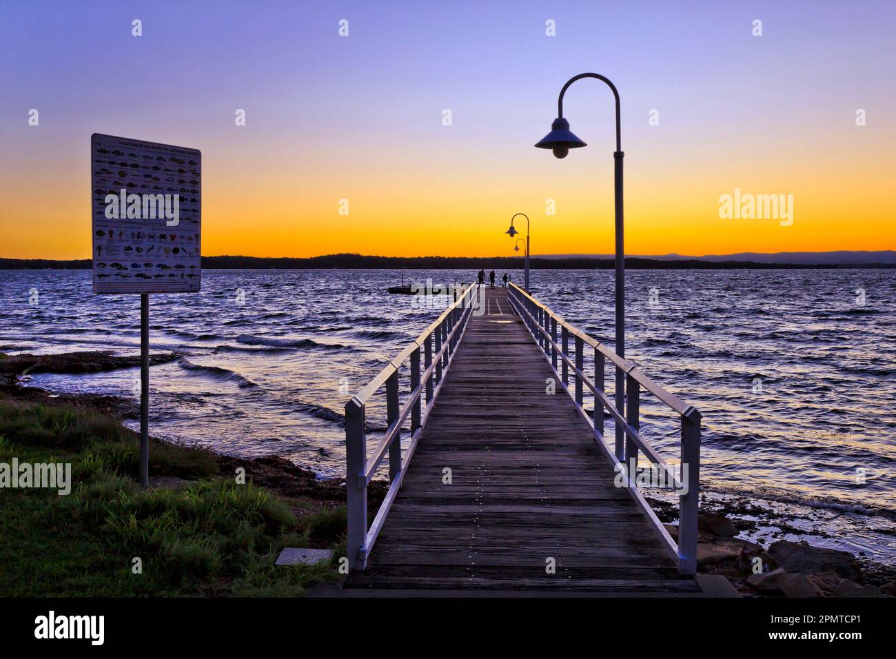 Setting sun over horizon over Lake Macquarie from timber fishing jetty