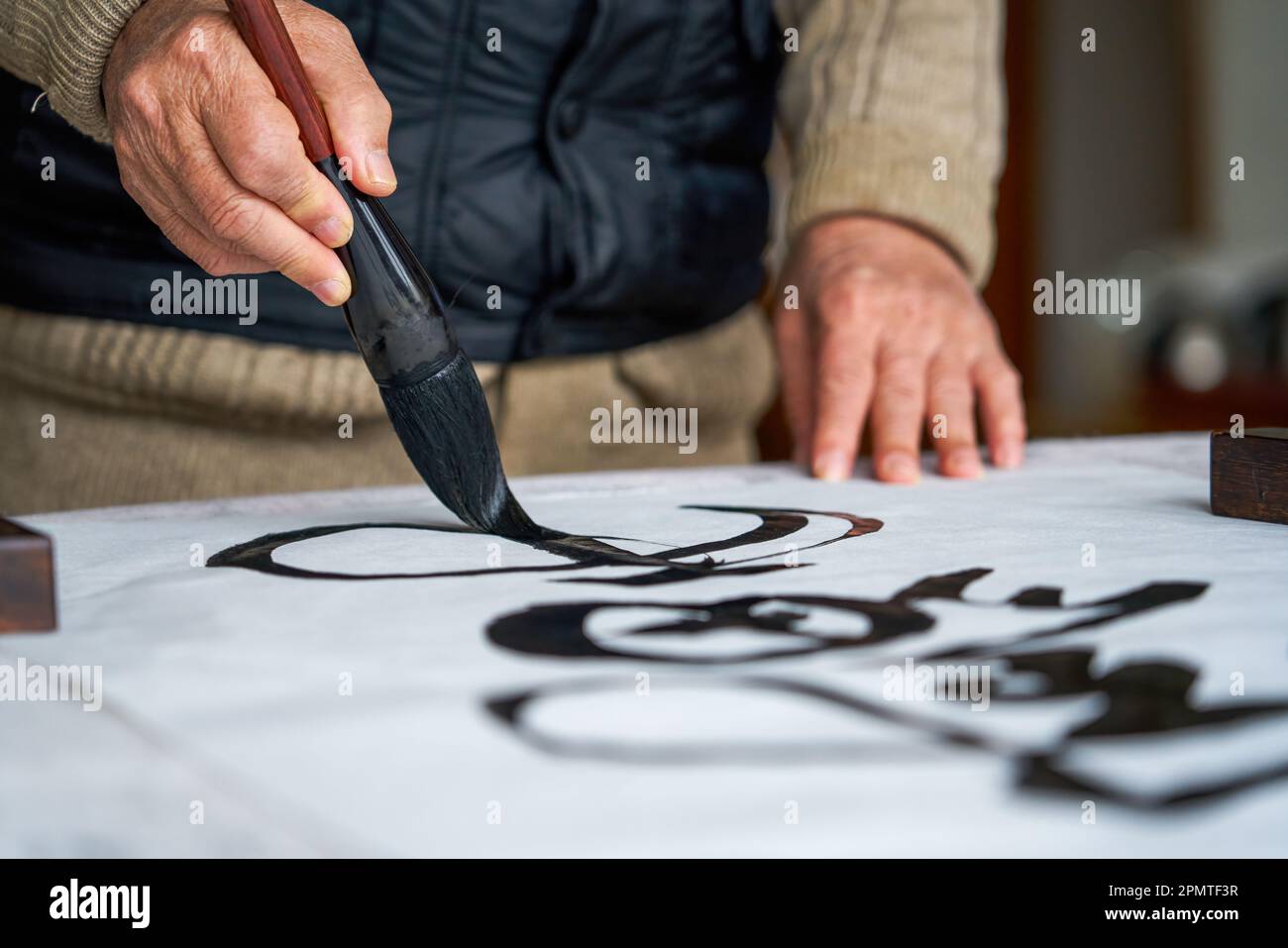 An old Chinese calligrapher is creating and writing calligraphy works. Translation carry on the