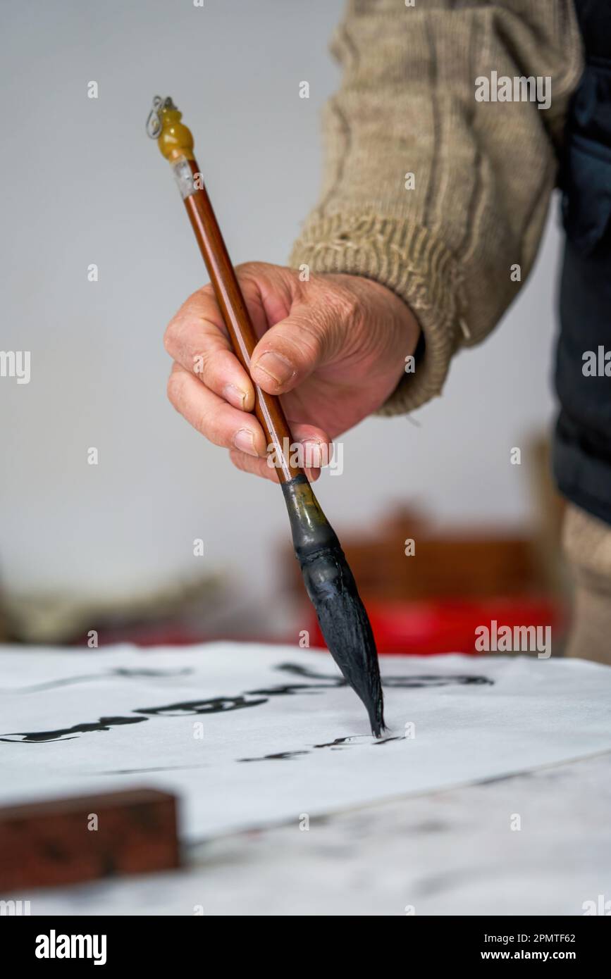 An old Chinese calligrapher is creating and writing calligraphy works. Translation carry on the