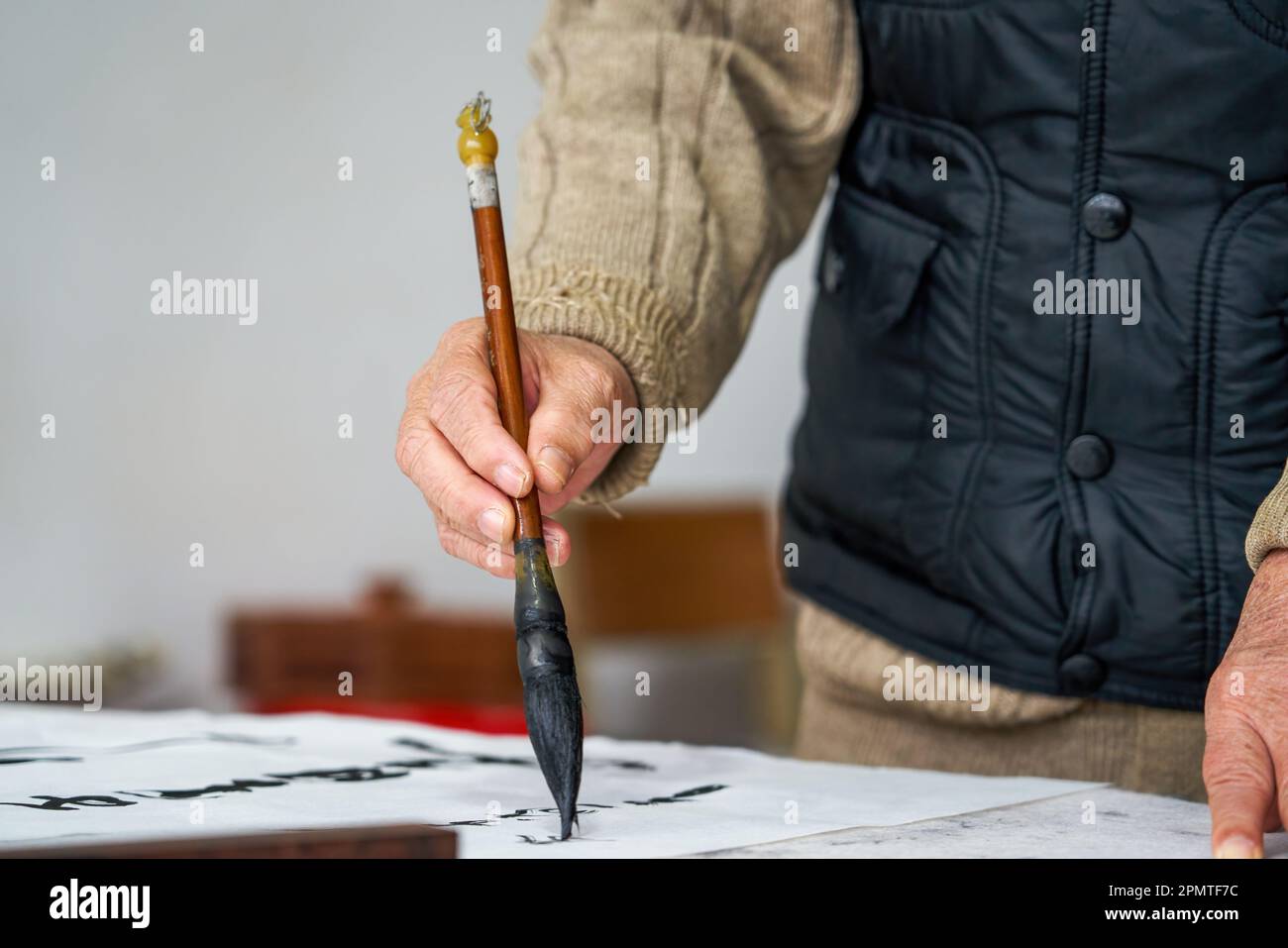 An old Chinese calligrapher is creating and writing calligraphy works. Translation carry on the
