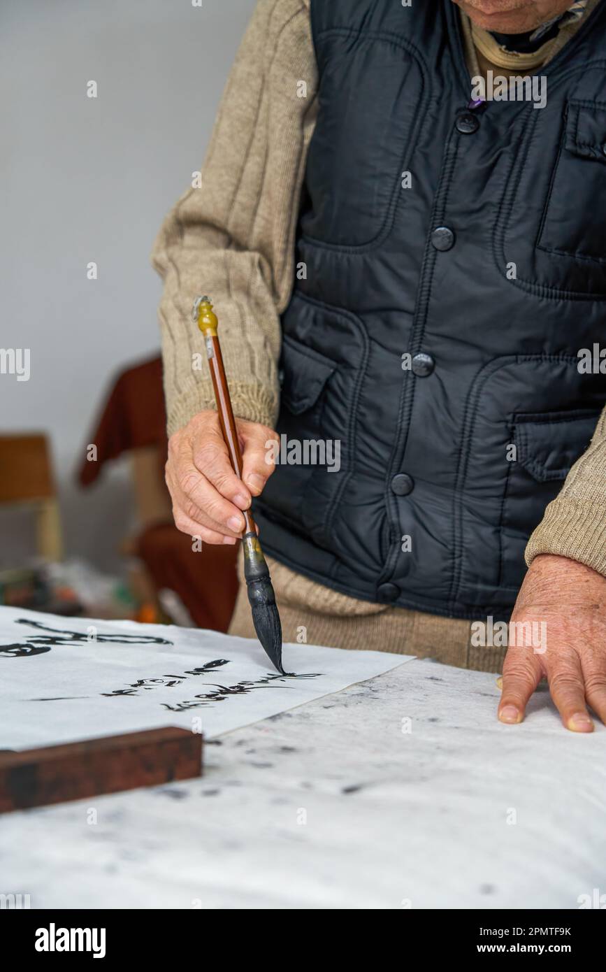 An old Chinese calligrapher is creating and writing calligraphy works. Translation carry on the