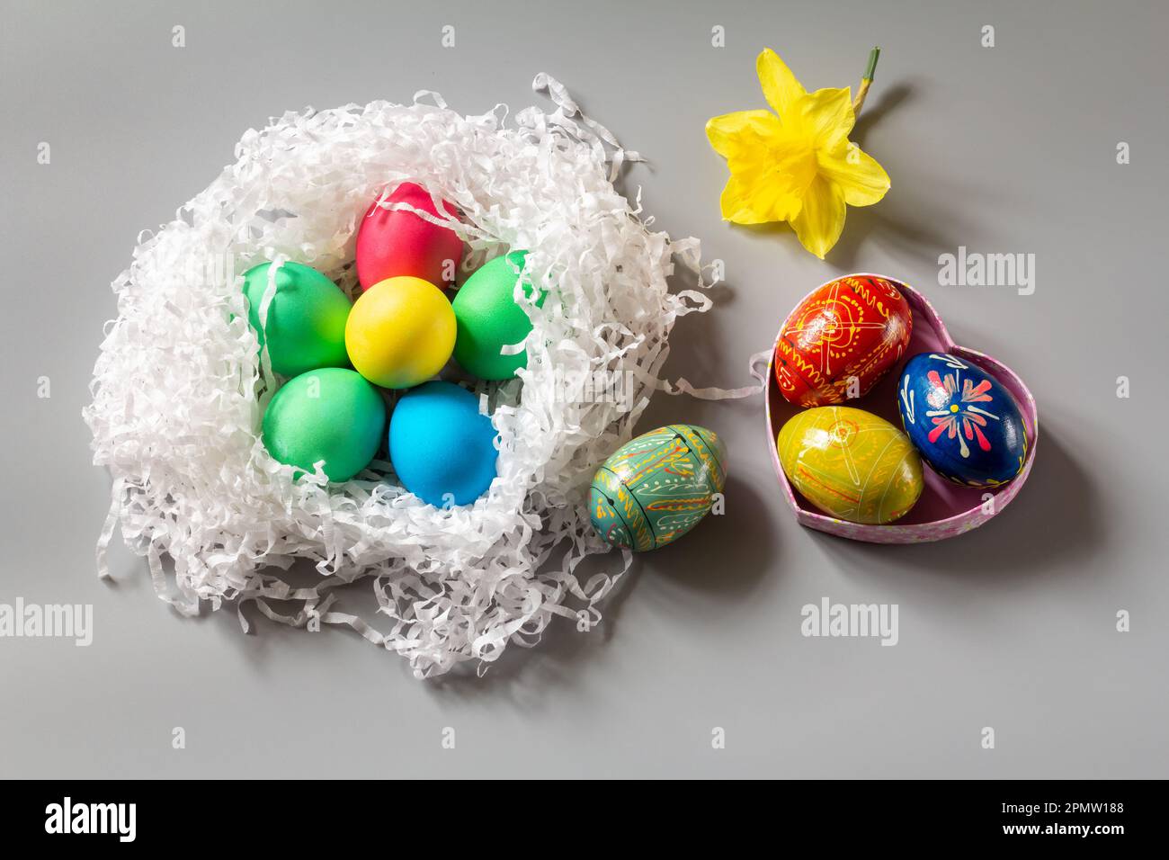 Nest with colored Easter eggs and daffodil flower Stock Photo - Alamy