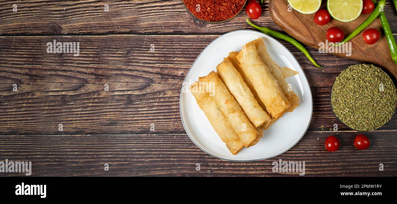 Cigarette pastry. Cheese pie on wood floor. Fried cheese rolls with phyllo. Local name sigara boregi. Top view. Empty space for text. copy space Stock Photo