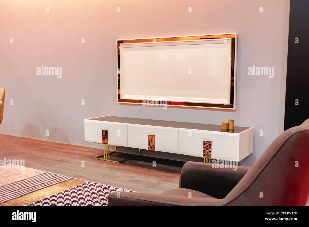 White and gold-plated TV cabinet in the interior of the room. Stock Photo