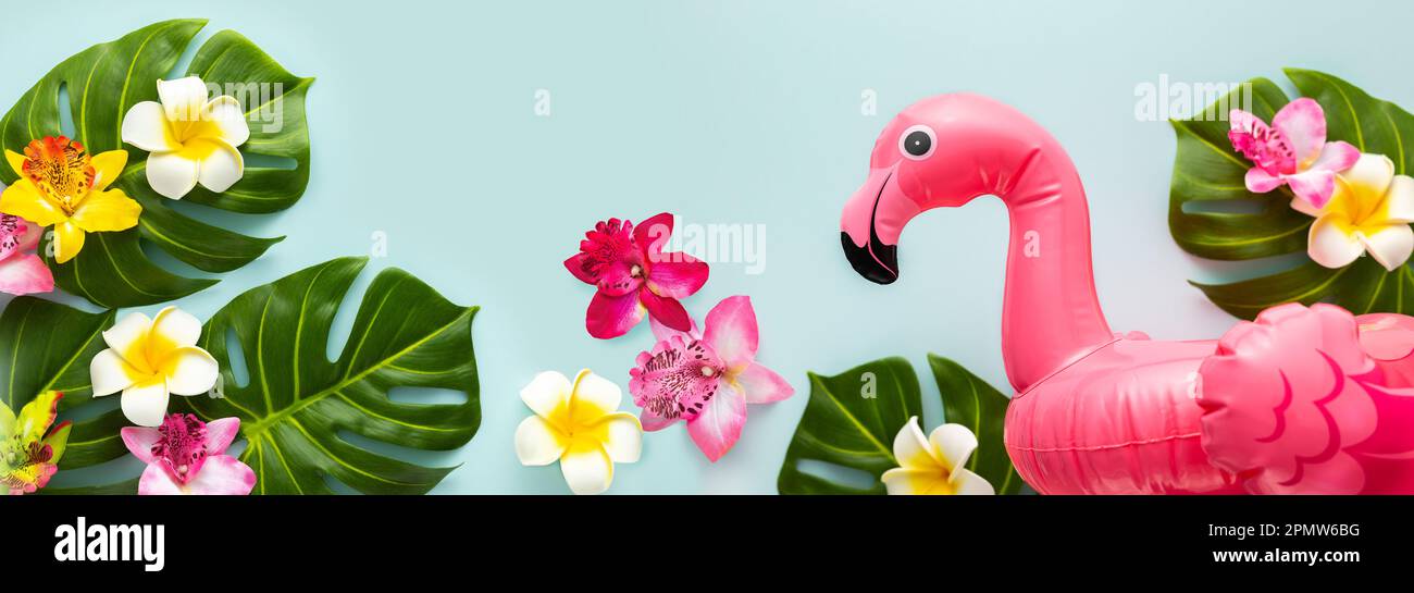 Pink flamingo, tropical leaf monstera and orchid flowers on light background. Summer beach party concept. Flat lay, copy space. Stock Photo