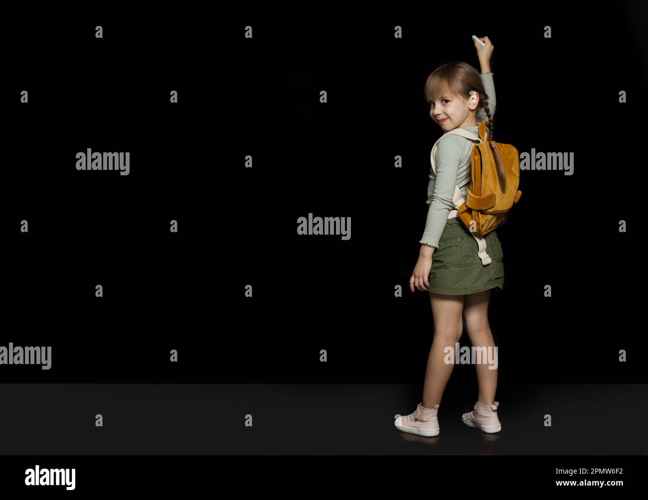 Smiling child girl with backpack writing on school chalkboard. Back to ...