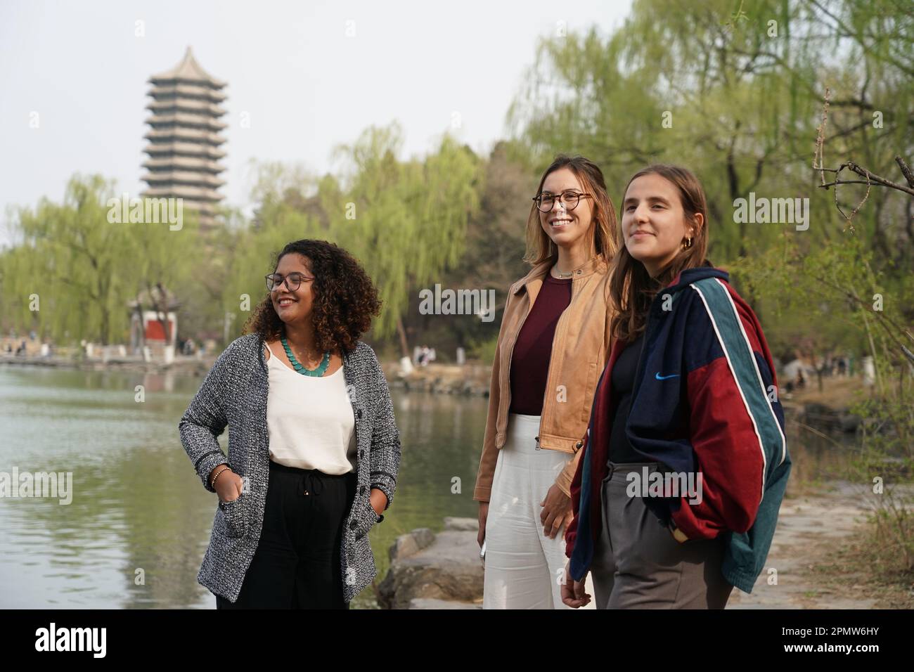 (230415) -- BEIJING, April 15, 2023 (Xinhua) -- Rafaela (L), Manuela (C) and Maria pose for a photo near the Weiming Lake of Peking University in Beijing, capital of China, March 31, 2023. Maria Eduarda Variani, Rafaela Viana dos Santos, Manuela Boiteux Pestana, and Marco Andre Rocha Germano are Brazilian students studying in the Master of China Studies program at the Yenching Academy of Peking University in China. The four of them have been interested in Chinese culture since they were young. After arriving in Beijing, they have been impressed by the Chinese capital's profound cultural he Stock Photo