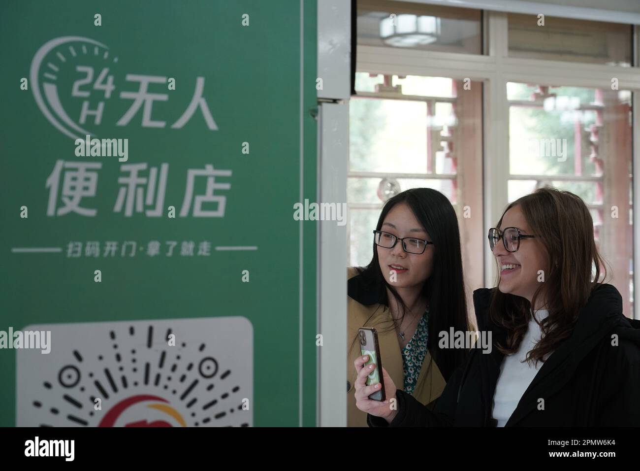 (230415) -- BEIJING, April 15, 2023 (Xinhua) -- Maria (R) scans a QR code on a vending machine at the Yenching Academy of Peking University in Beijing, capital of China, April 13, 2023. Maria Eduarda Variani, Rafaela Viana dos Santos, Manuela Boiteux Pestana, and Marco Andre Rocha Germano are Brazilian students studying in the Master of China Studies program at the Yenching Academy of Peking University in China. The four of them have been interested in Chinese culture since they were young. After arriving in Beijing, they have been impressed by the Chinese capital's profound cultural herit Stock Photo