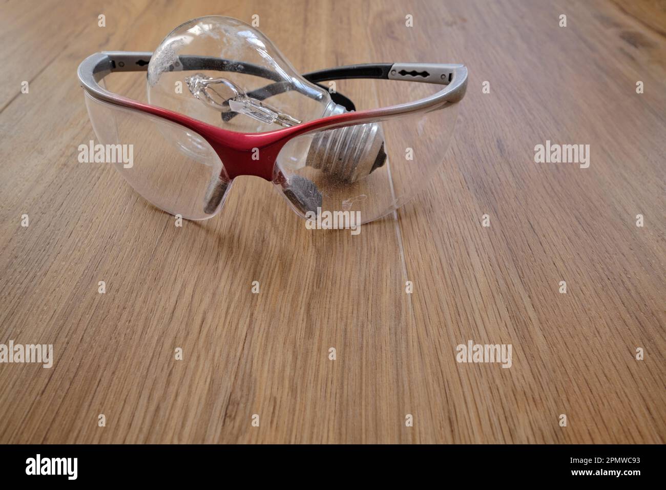 Used incandescent light bulb and plastic protective glasses on a wooden ...