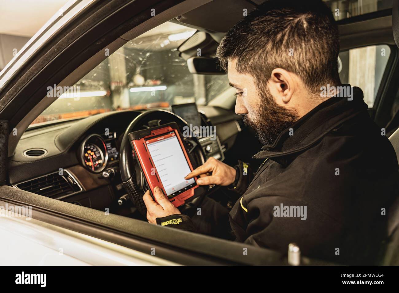 A mechanic's hands use a diagnostic tool to troubleshoot a modern car's