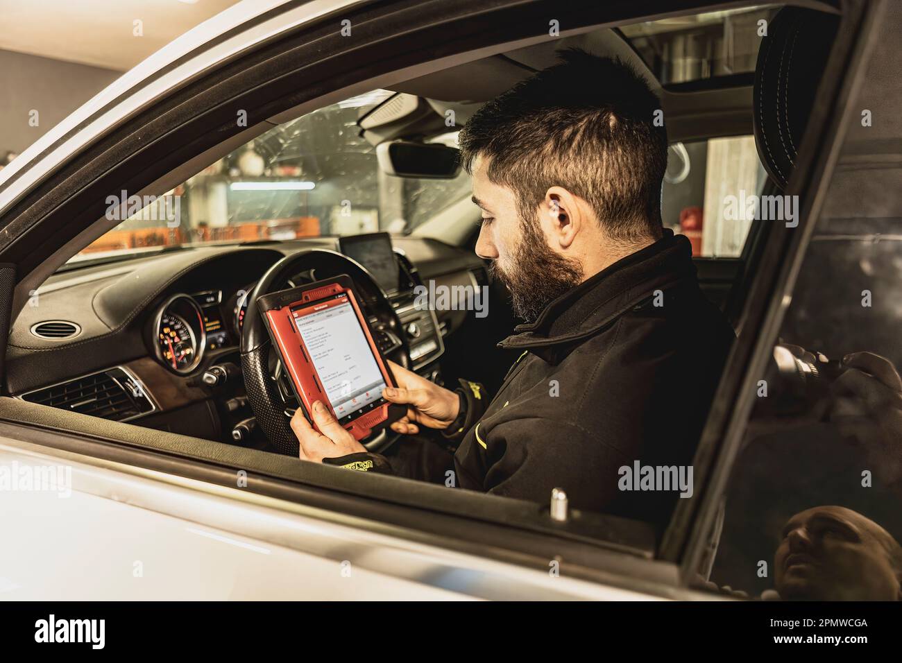 A mechanic's hands use a diagnostic tool to troubleshoot a modern car's