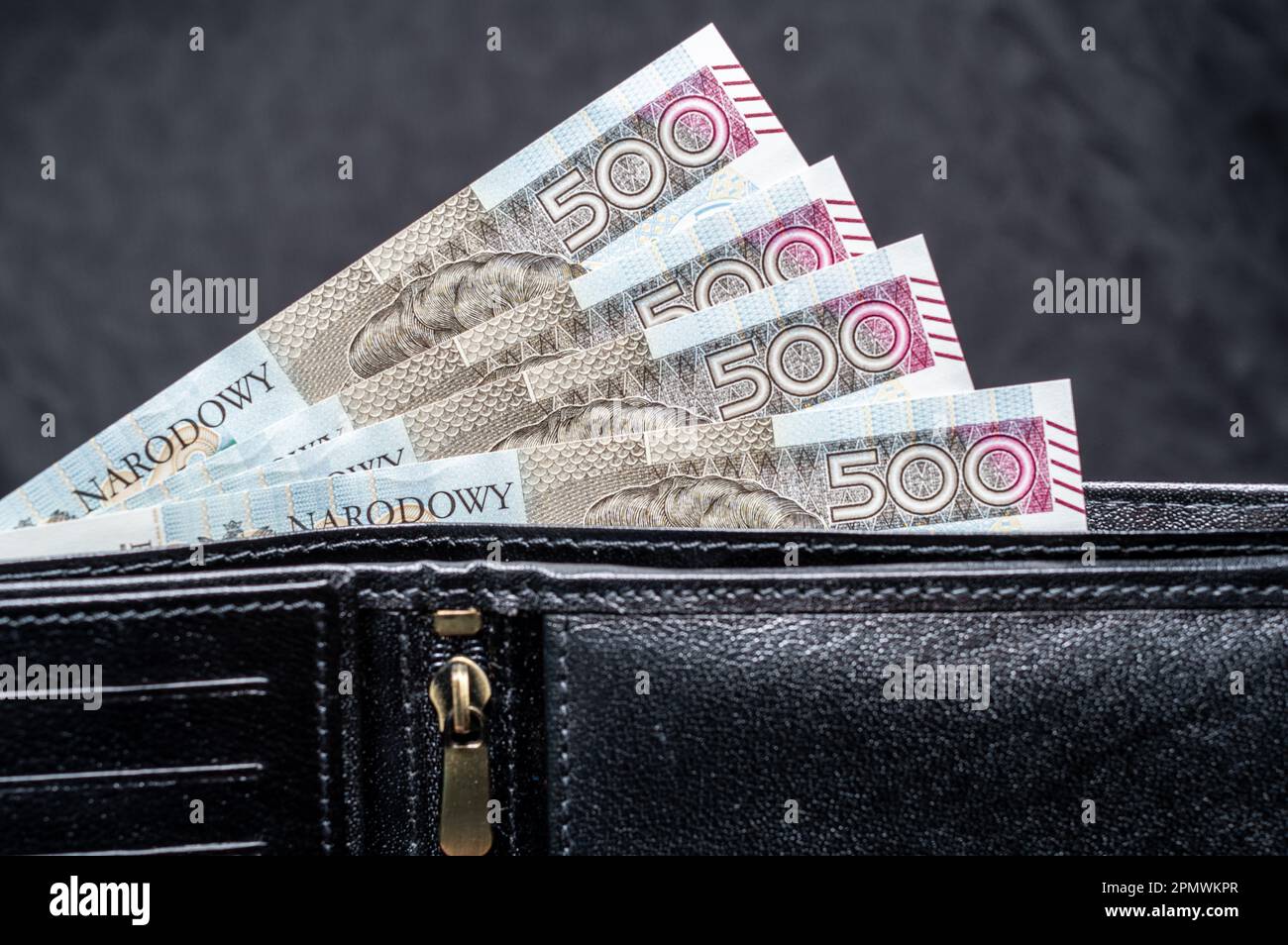 A closeup shot of 500 zloty bills protruding from a leather black wallet Stock Photo