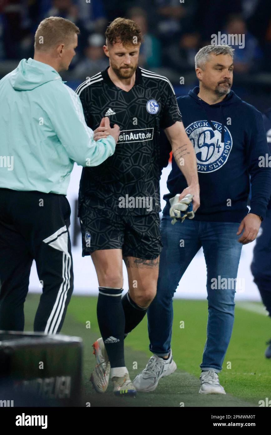 Gelsenkirchen, Deutschland, 1. Fussball Bundesliga 28. Spieltag FC Schalke 04 vs.Hertha BSC Berlin 5:2 am 14. 04. 2023 in der Veltins Arena auf Schalke  in Gelsenkirchen Torwart Ralf FÄHRMANN (FAEHRMANN )(S04) -2R-  muss verletzt vorzeitig das Spielfeld verlassen und wird von Co-Trainer Markus GELLHAUS (S04)   -L- und Trainer Thomas REIS (S04) -R- getröstet Foto: Norbert Schmidt, Duesseldorf Stock Photo