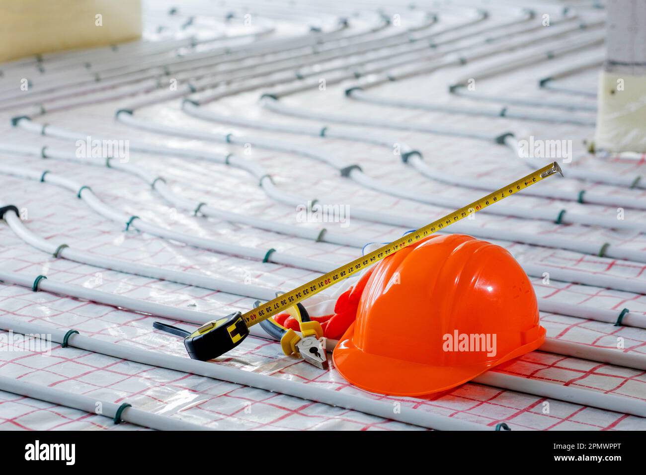 Tools for repair hard hat, plier, glove on warm floor. Installation of