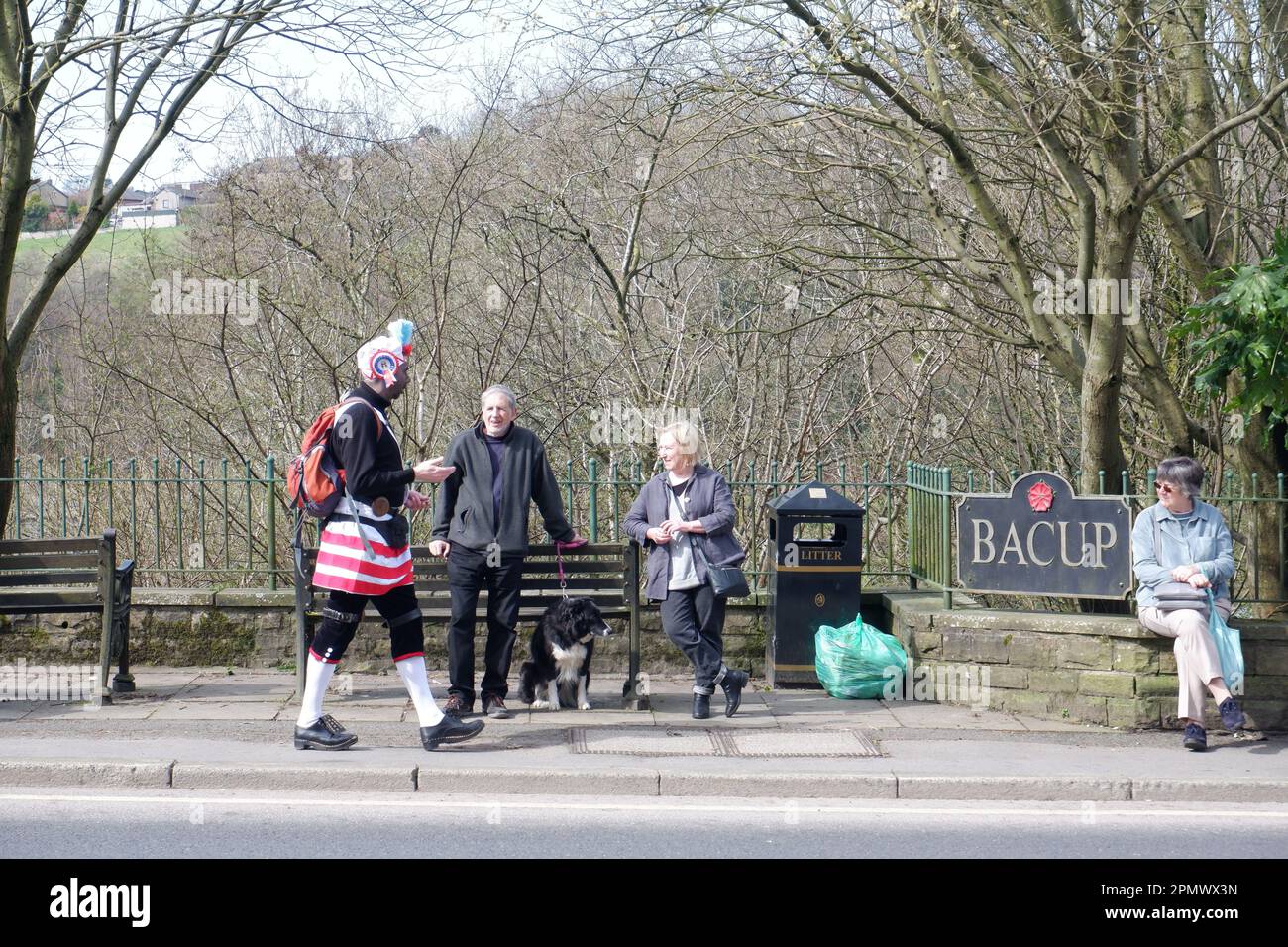 Member of Britannia Coconutters walking past spectators in front of town sign during perambulation of Bacup in Lancashire on Easter Saturday Stock Photo