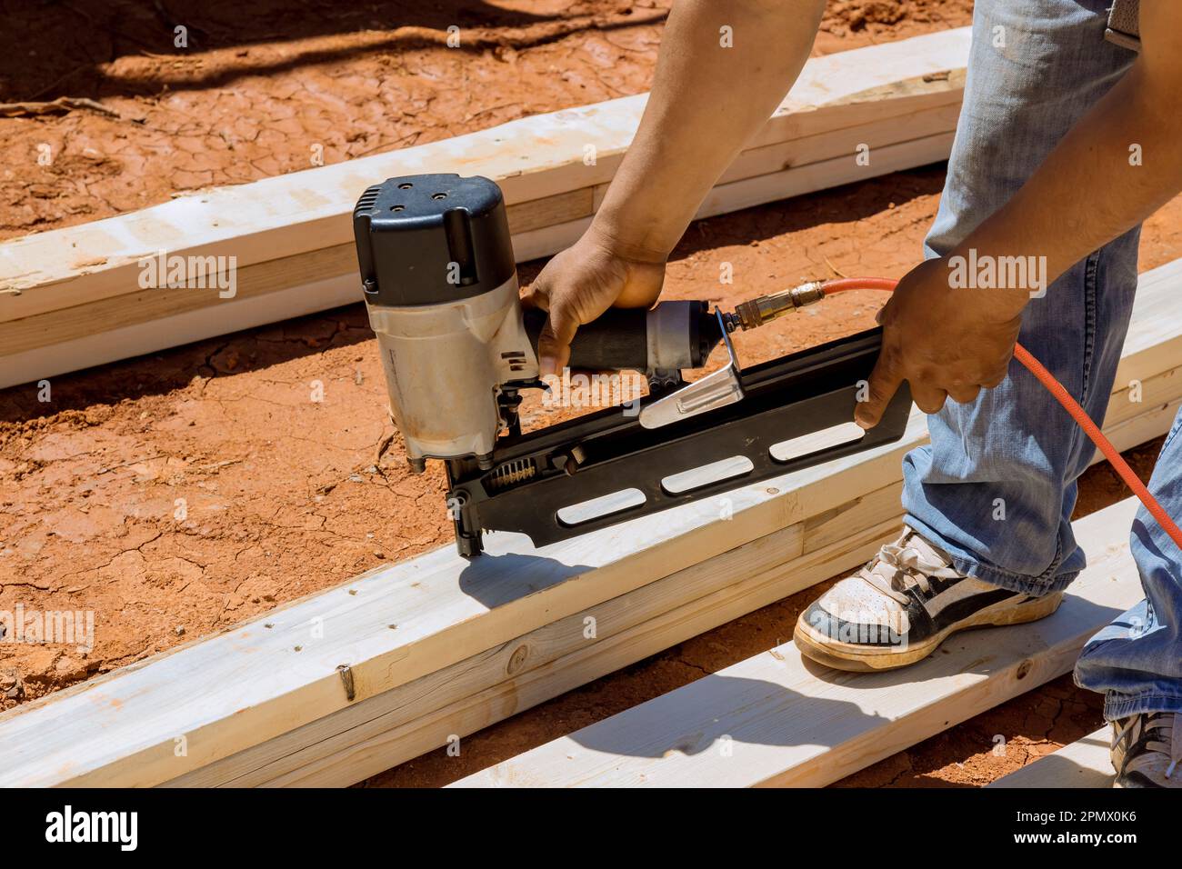 Using an air hammer contractor nails wooden beams to frame of housing ...