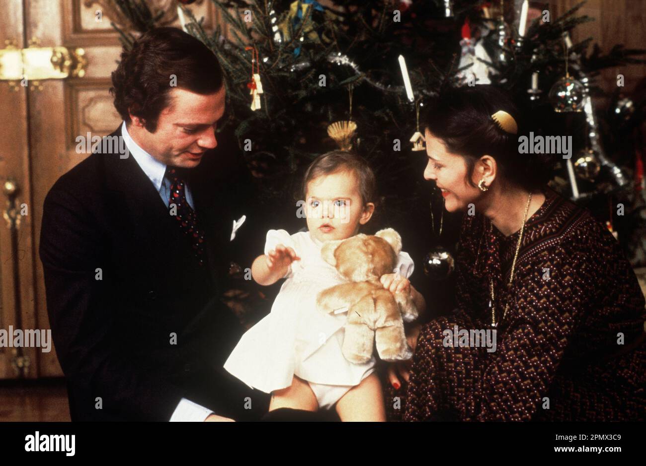 Swedish royal family in the 1970s. King Carl XVI Gustaf with queen Silvia and their daughter crownprincess Victoria in front of the christmas tree in the royal castle in Stockholm Sweden 1978. Stock Photo
