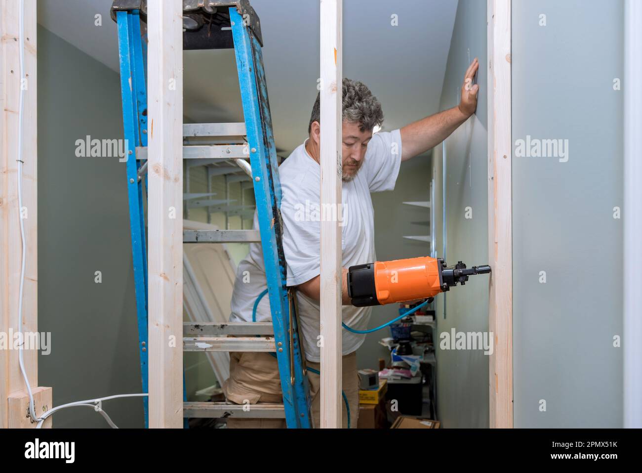 Building home using an air hammer to nail wooden beams framework of ...