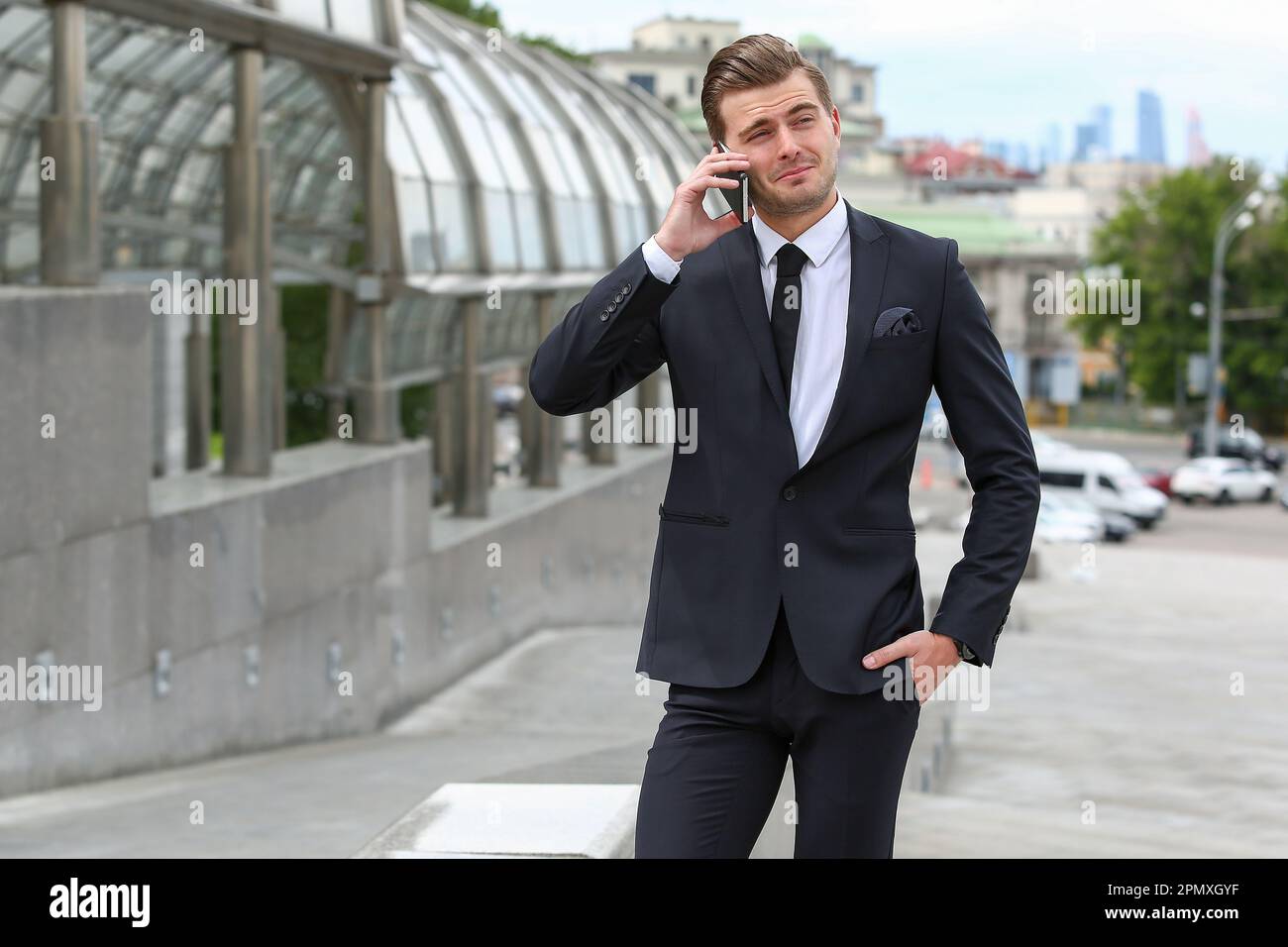 A business man in a black suit poses on a city street Stock Photo - Alamy