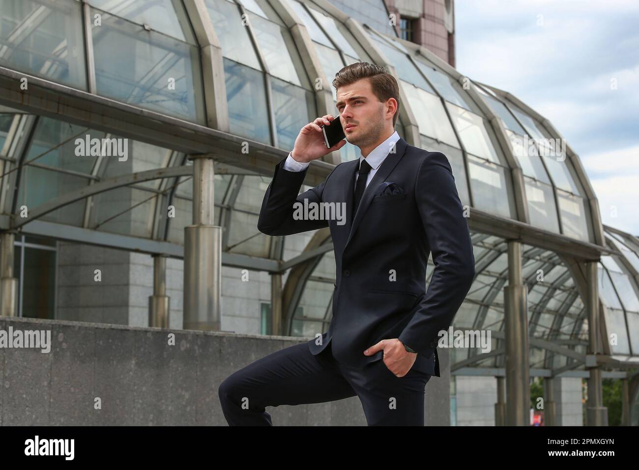 A business man in a black suit poses on a city street Stock Photo - Alamy