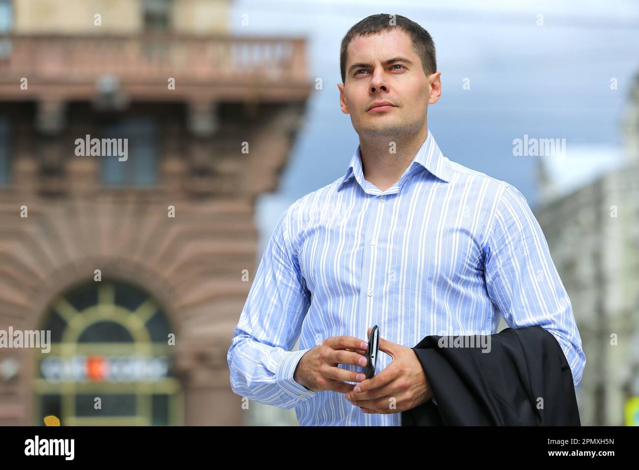 A business man in a black suit poses on a city street Stock Photo - Alamy