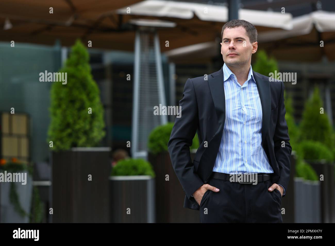 A business man in a black suit poses on a city street Stock Photo - Alamy