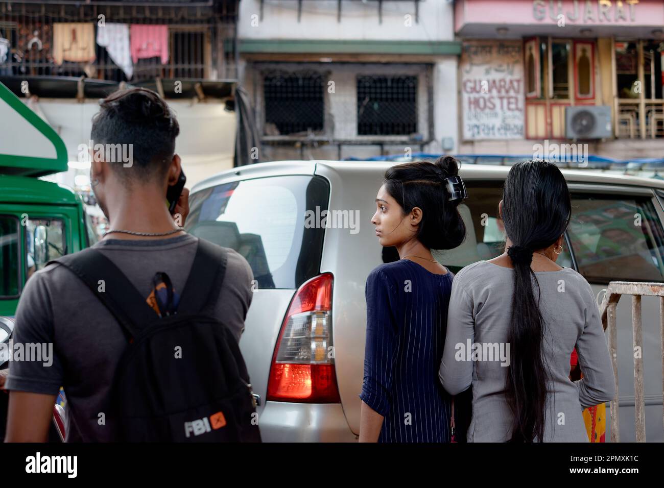 Two young Indian women and a random male passer-by in a street in Pydhonie area, Mumbai, India Stock Photo