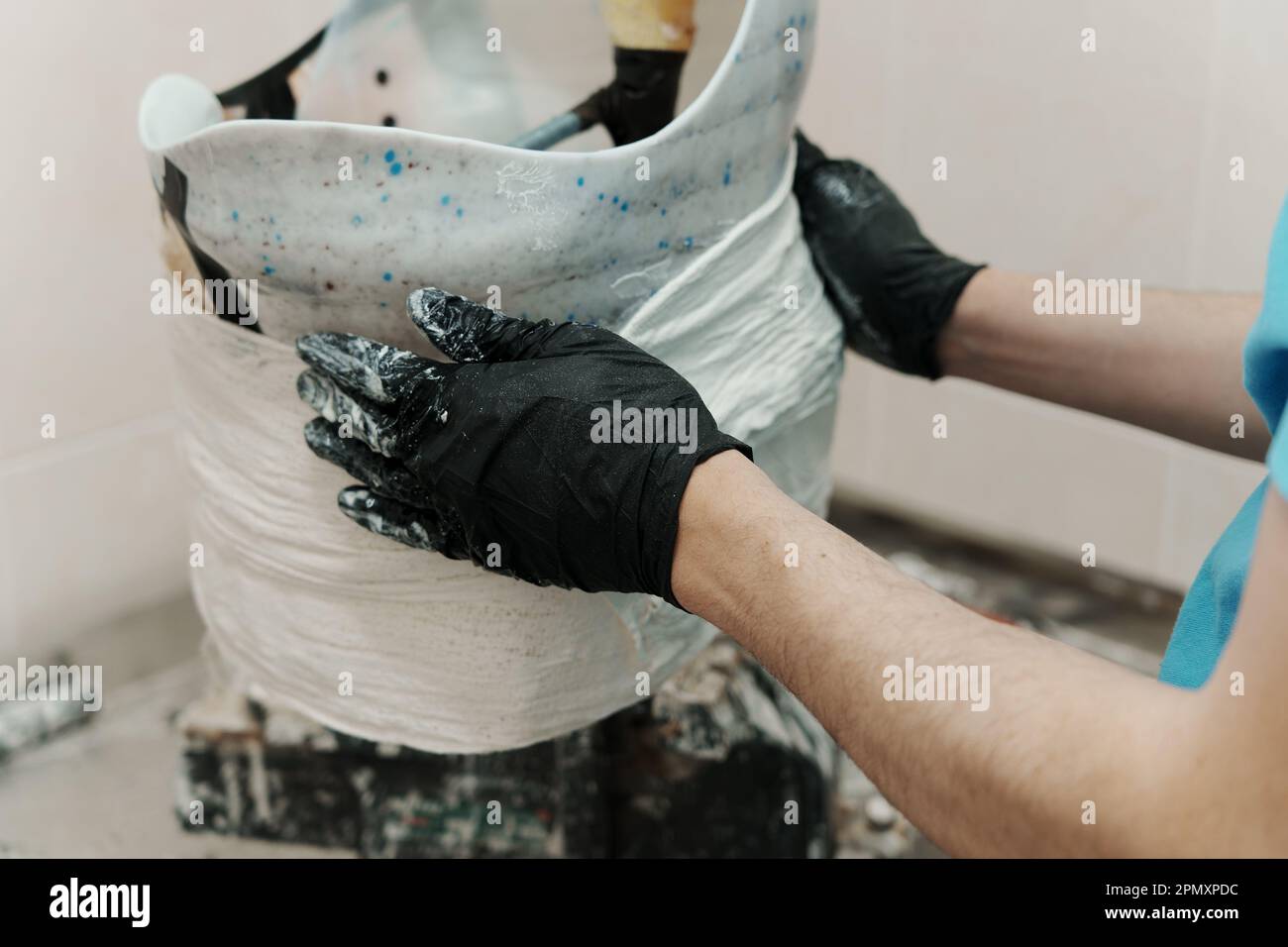 Male worker in black rubber gloves making hip disarticulation