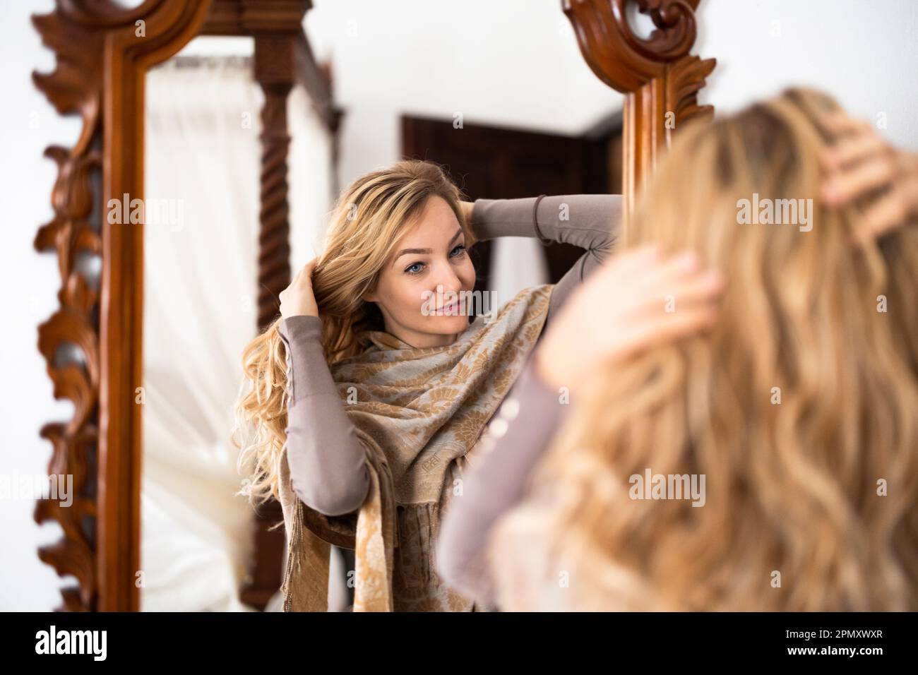 Pretty, young woman getting ready to go out in front of a mirror Stock