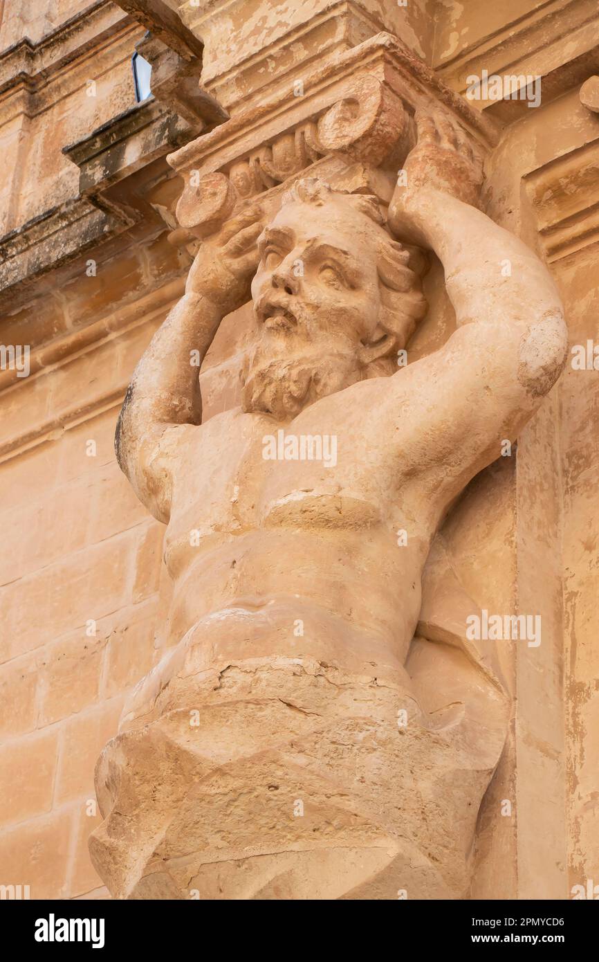 Mdina, Malta - November 13, 2022: Detail of the facade of St Paul's Cathedral Museum, an atlantid, male figures as pilasters, limestone statue holding Stock Photo