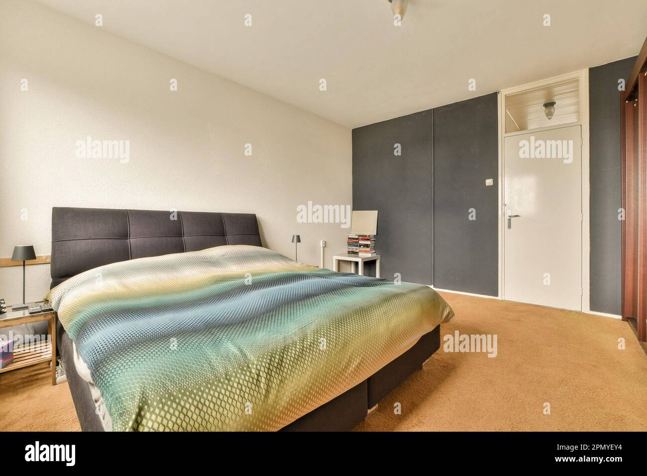 a bedroom with a bed, dressers and tv in the corner on the left side of