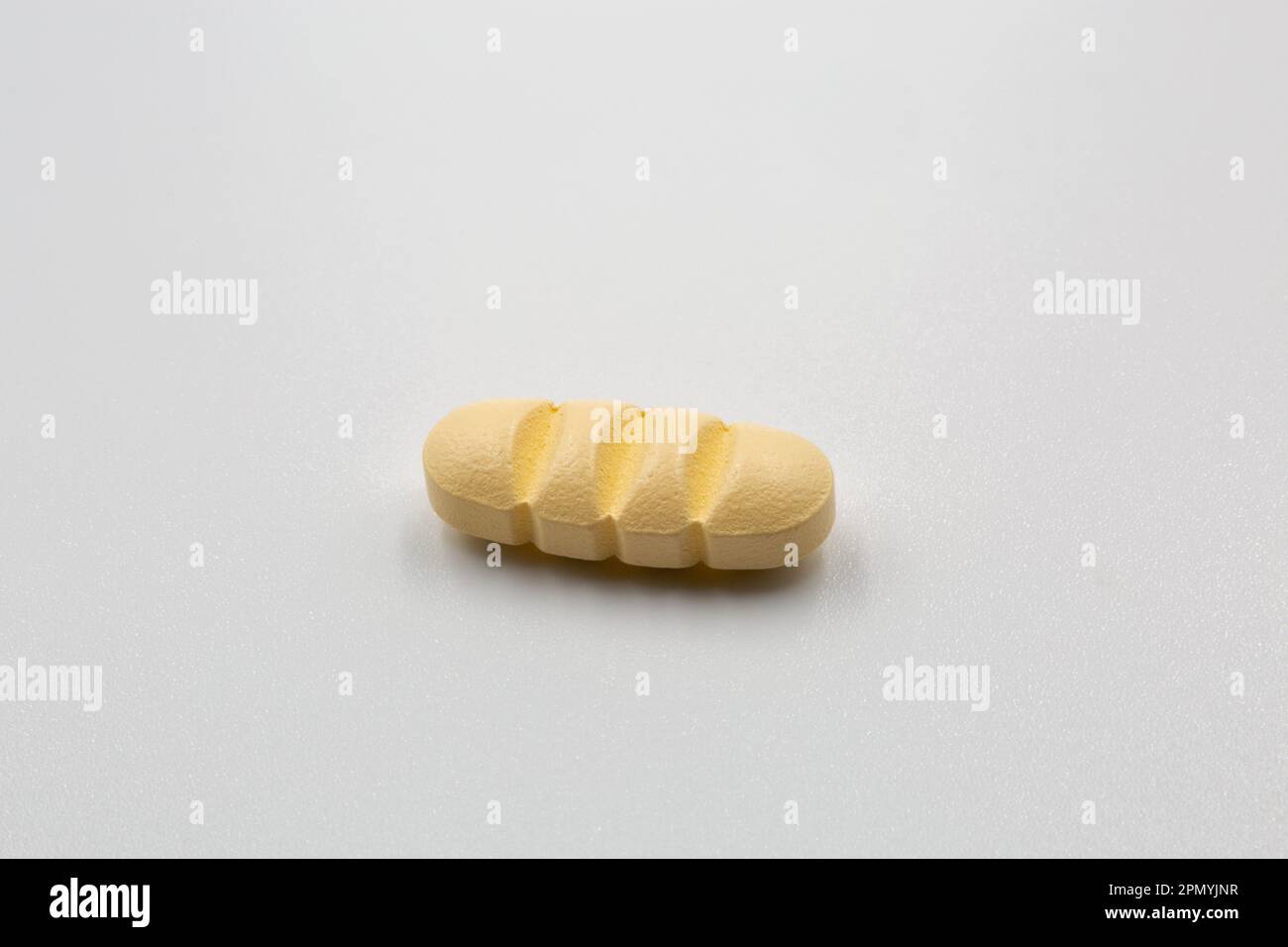 Yellow oblong tablet with dividing strips for dividing into four parts closeup on white. Stock Photo